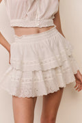 White lace skirt worn by a person on a plain background