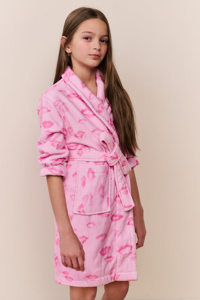 Young girl wearing a pink robe with heart patterns on a beige background