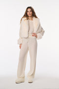 Woman wearing a cream-colored outfit with fur trim on a white background
