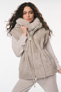 Woman wearing a gray quilted jacket with fur trim on a white background