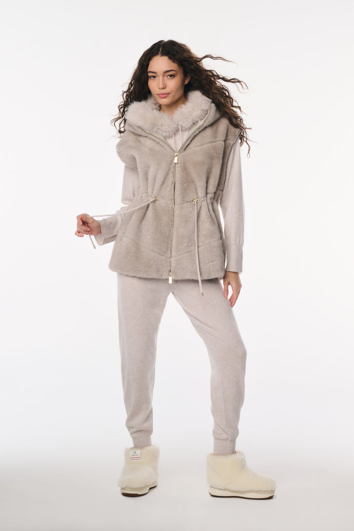 Woman wearing a gray hooded jacket with fur trim and matching pants on a white background
