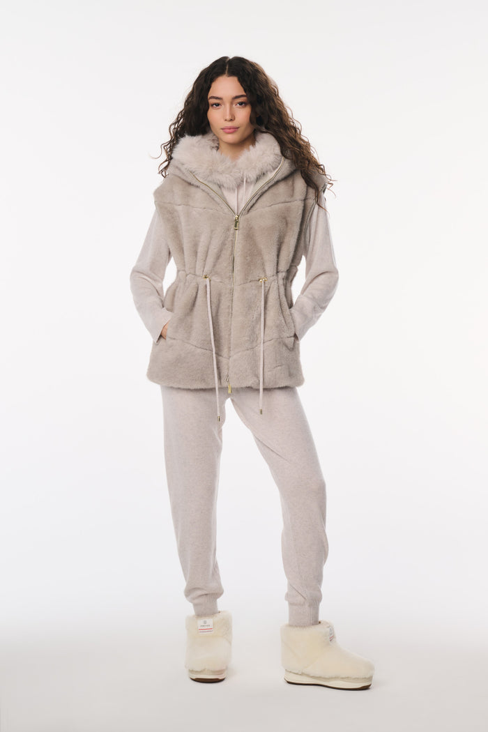 Woman wearing a beige hooded jacket and pants on a white background