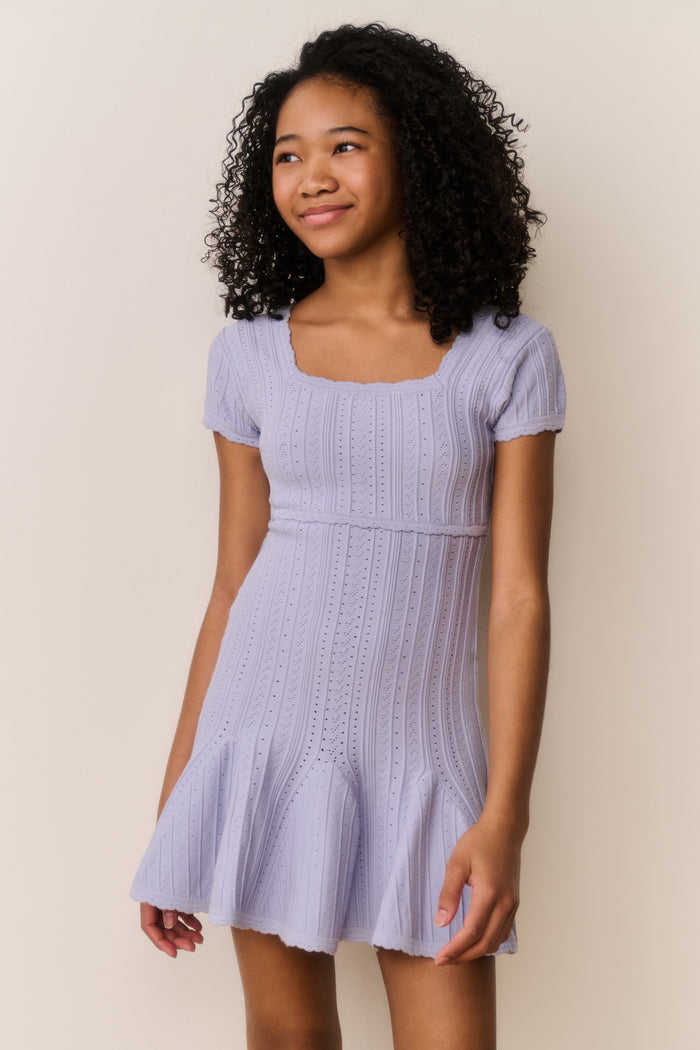 Young woman wearing a light purple dress against a plain background