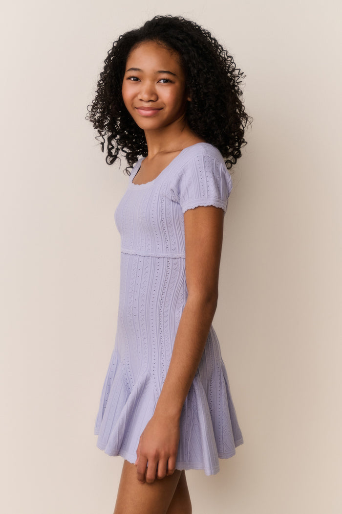 Girl wearing a light purple dress against a plain background